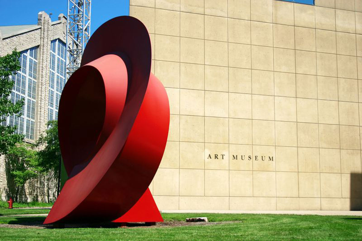 modern red metal sculpture in front of art museum
